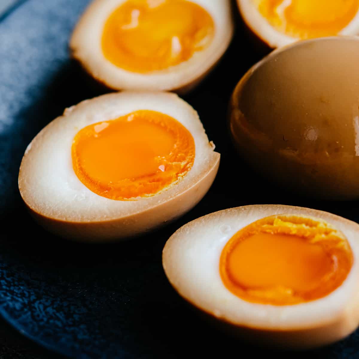 soy sauce eggs sliced in half on a black plate.