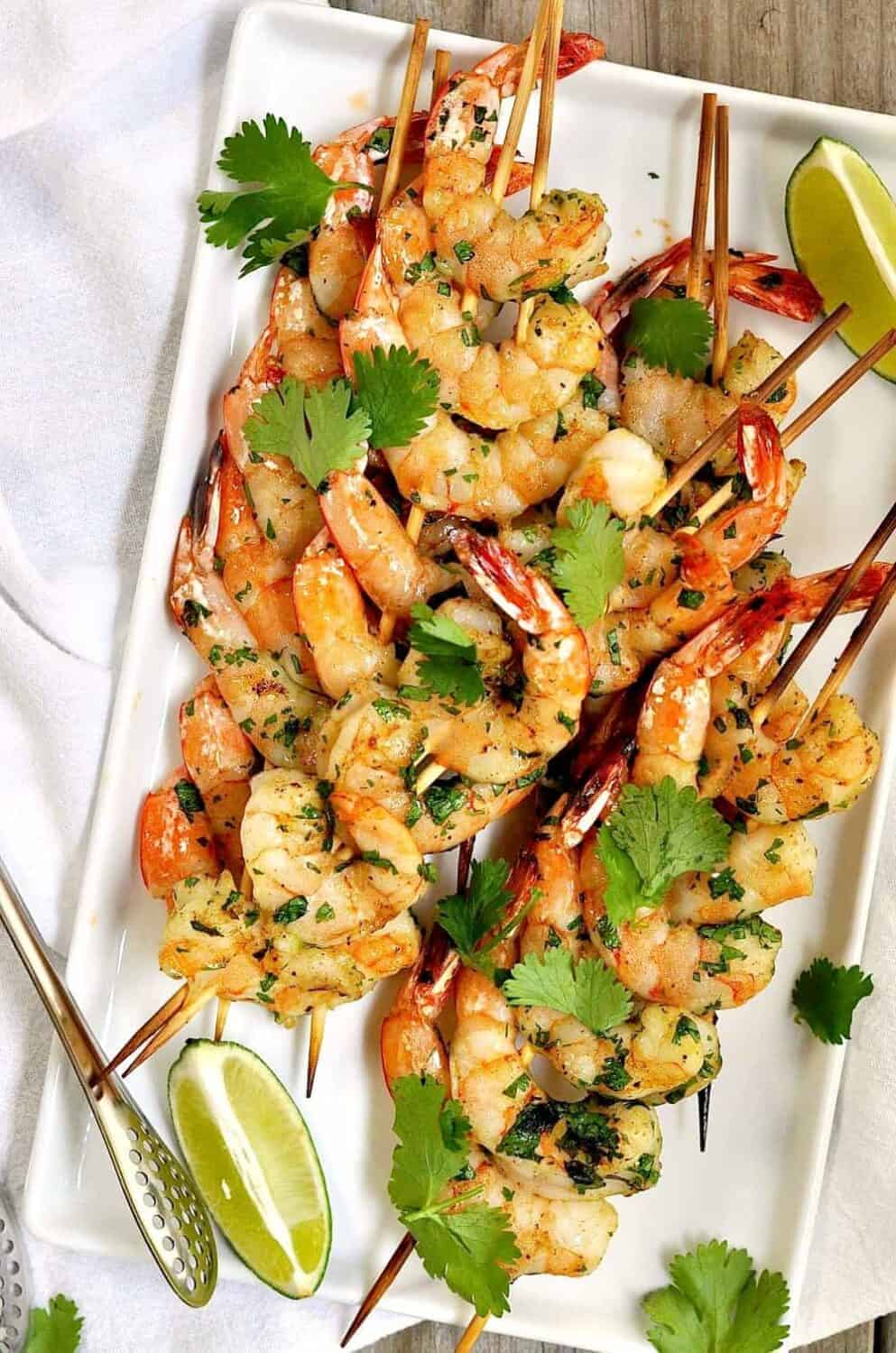 Spicy grilled shrimp are easy to assemble and cook in about 5 minutes. A simple marinade of cilantro with a kick of cayenne pepper make these a delicious and spicy-as-you-like addition to summer meals. String the shrimp onto two skewers to them very easy to turn on the grill.