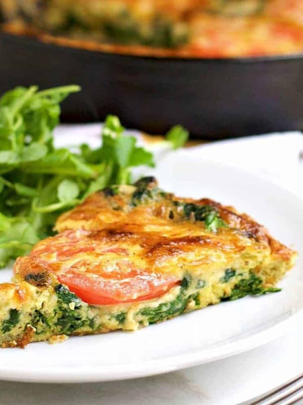 A wedge of Spinach Frittata served on a white plate.