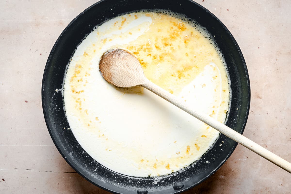 adding heavy cream to skillet.