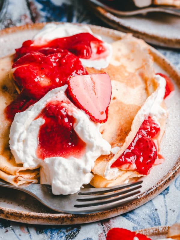 Strawberry Crepes served on ceramic plates and photographed at an angle.