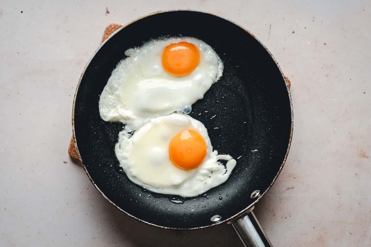 eggs frying in black nonstick skillet.