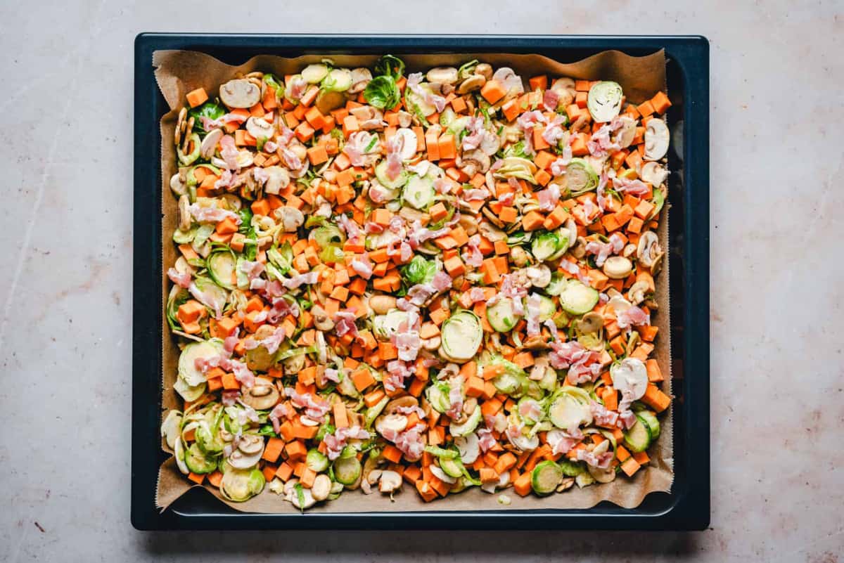 vegetables and bacon spread on baking sheet.