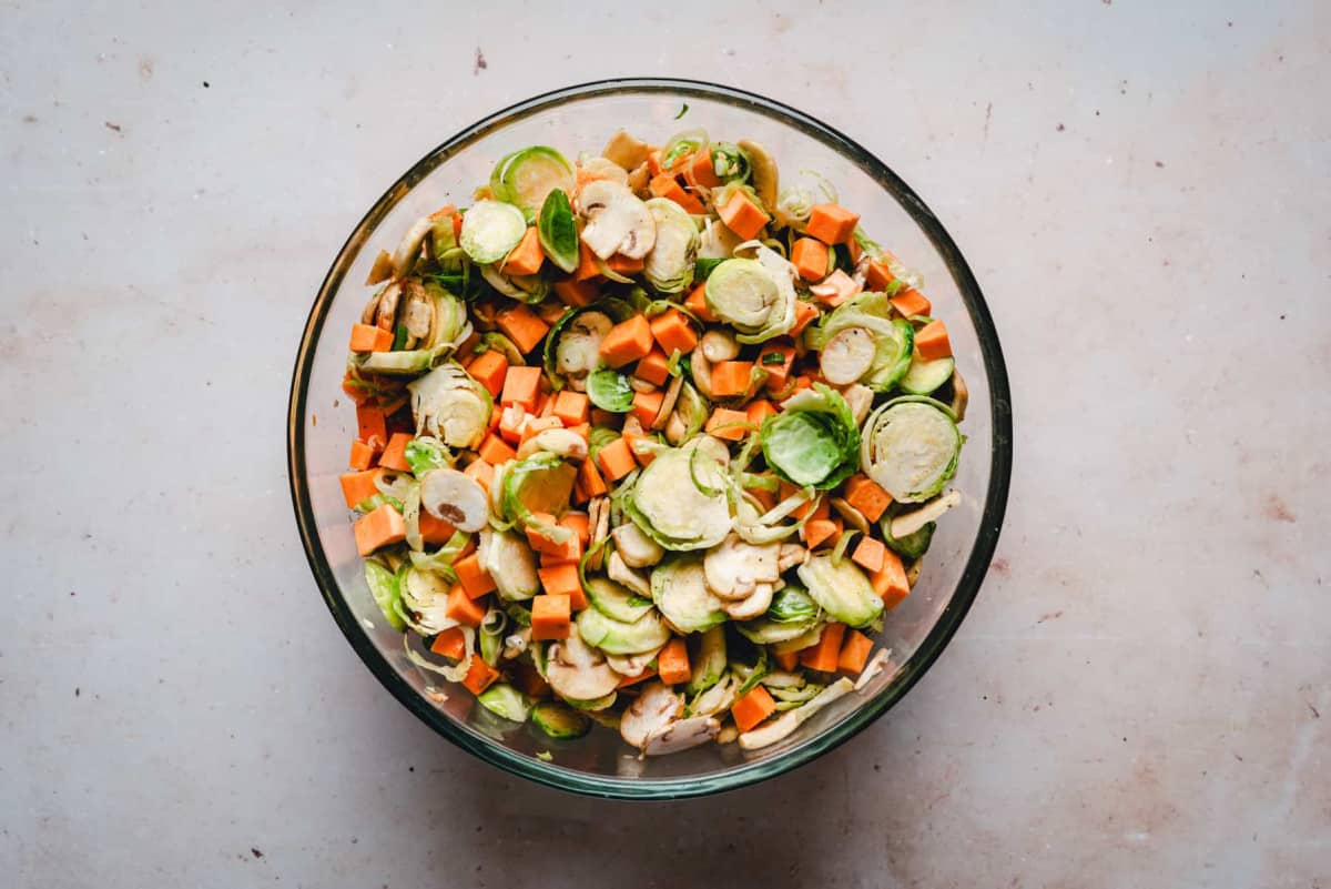 Sweet Potato Hash vegetables and seasoning mixed together in glass bowl.