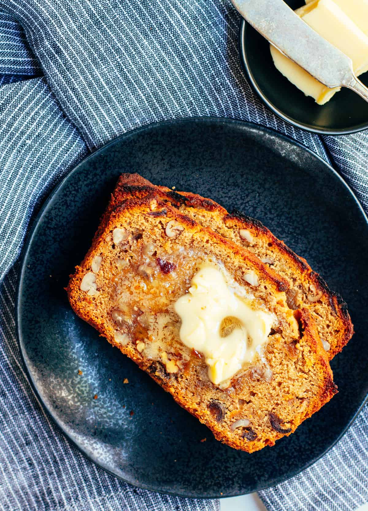 Toasted Slices of Sweet Potato Bread with butter on a black plate.