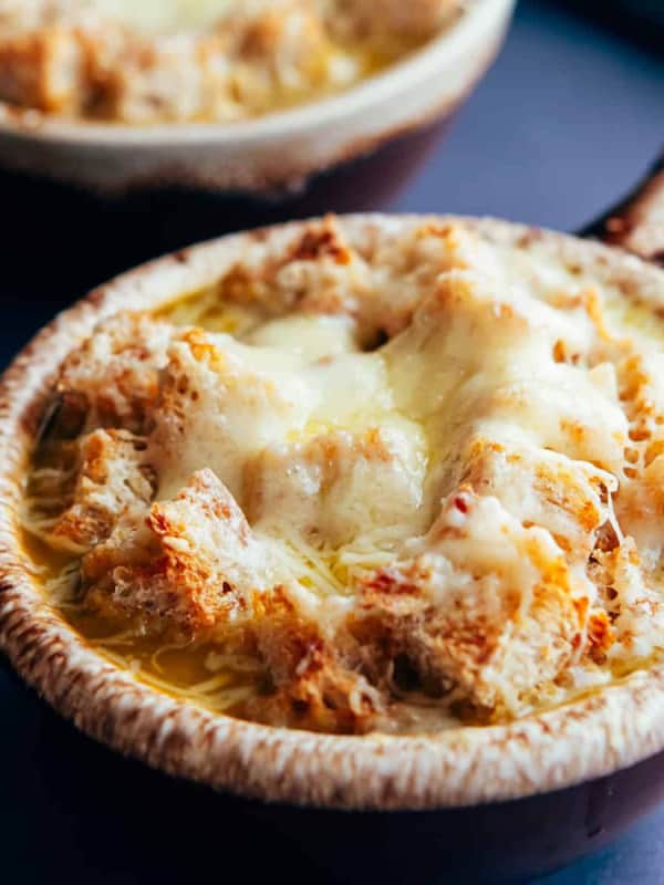 Vegetarian French Onion Soup served in traditional brown bowls with a long handle