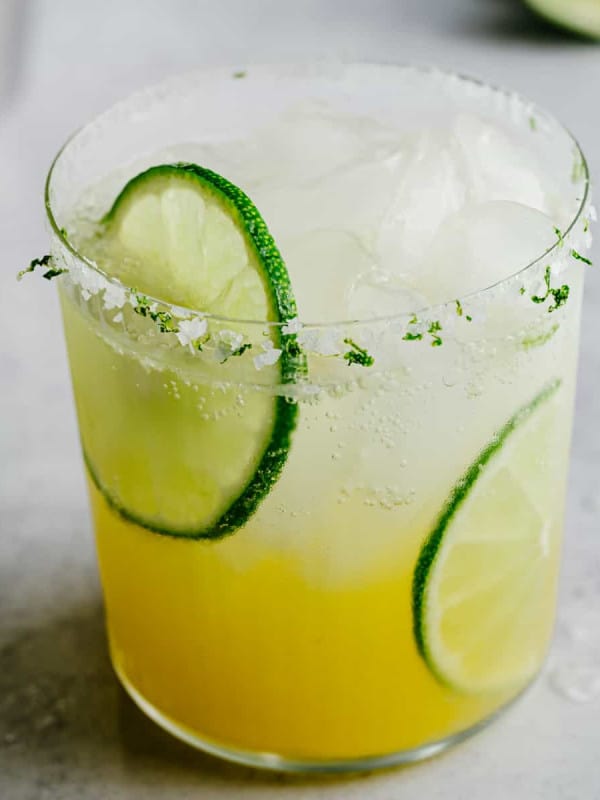 Virgin Margarita served in a highball glass with fresh lime slices and a salted rim.