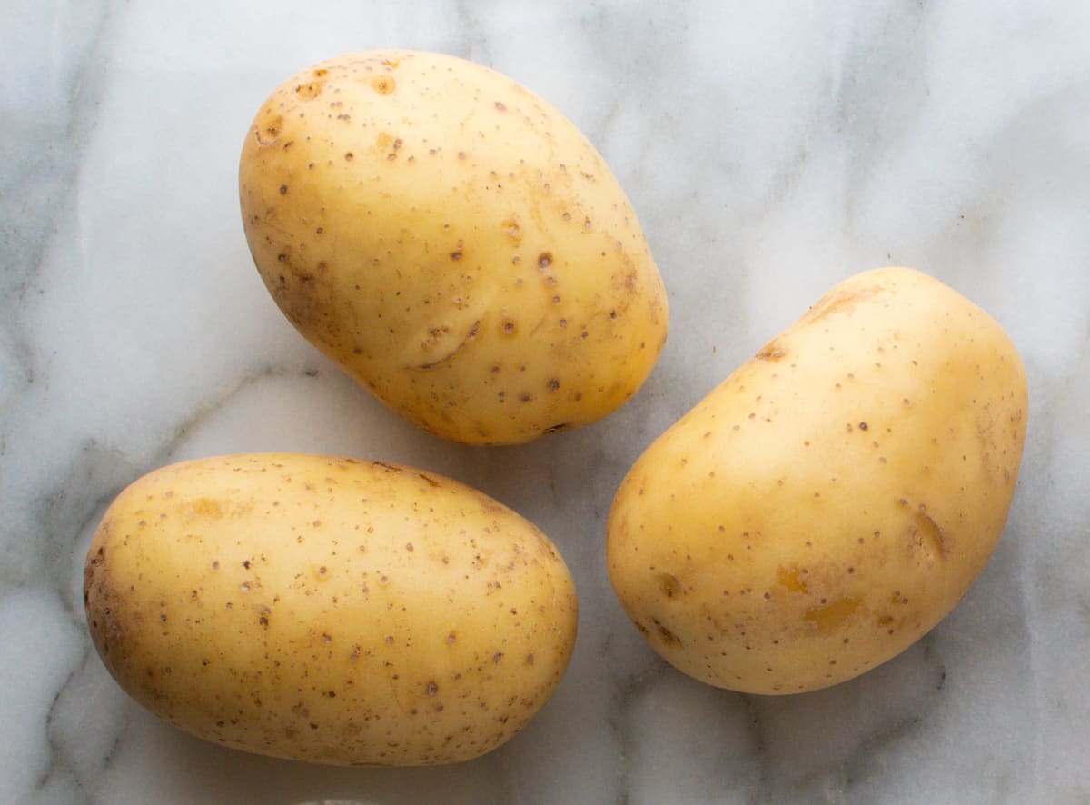 Yukon Gold Potatoes on a white marble board.