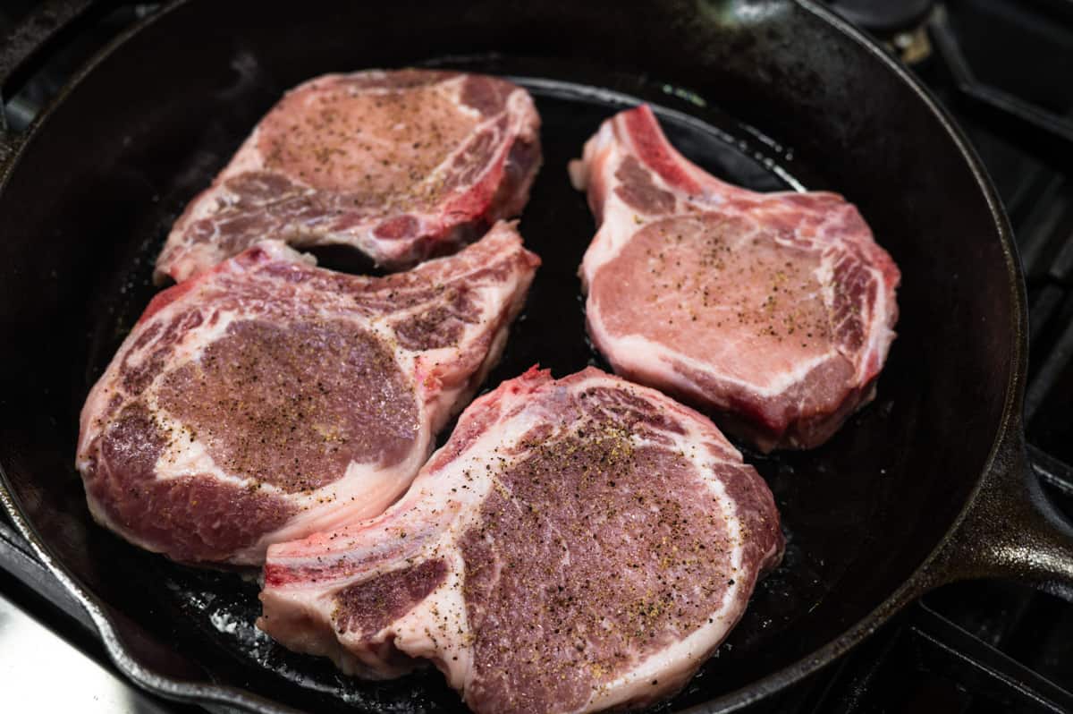 bone in pork chops in cast iron pan.