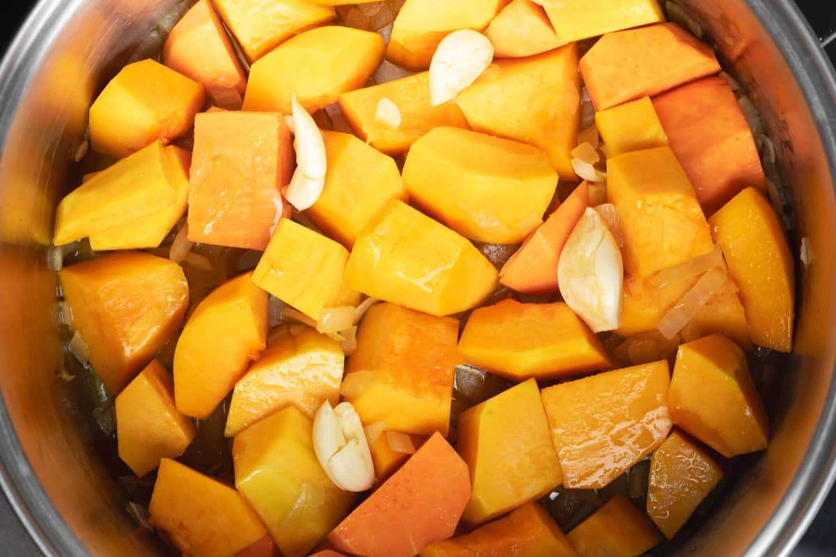 butternut squash sweet potato and garlic in a soup pot.