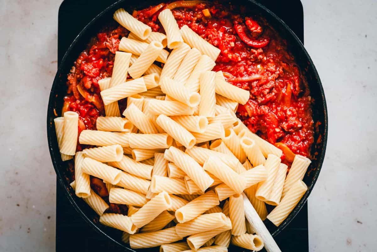 cooked rotini pasta added to sauce in skillet.