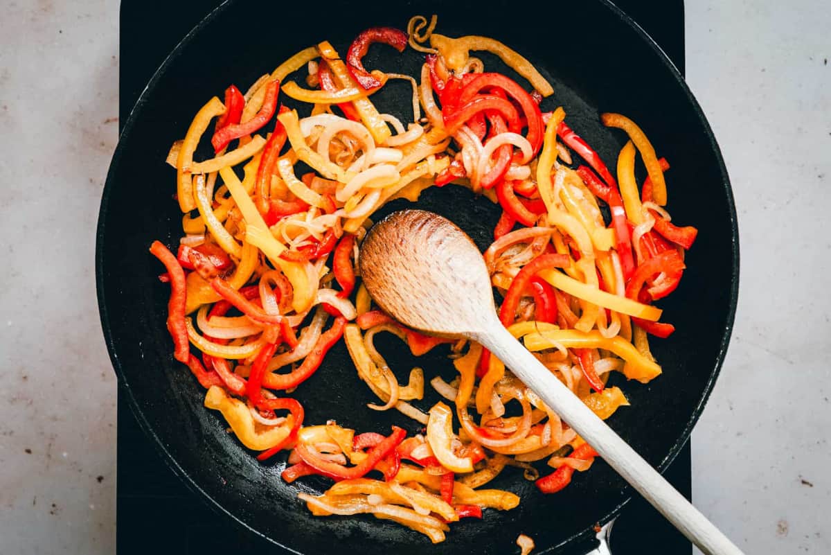 cooked sweet bell peppers and onions in a skillet.