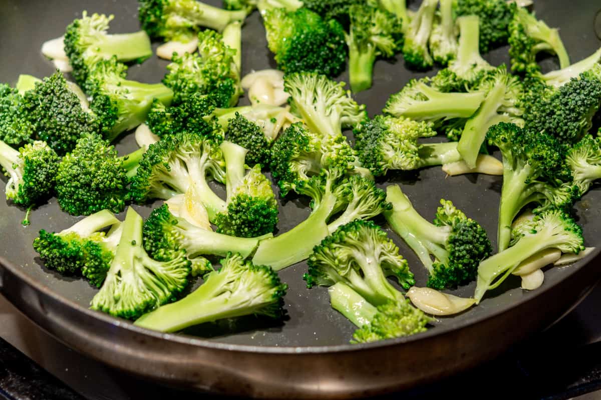 cooking broccoli and garlic in a skillet.