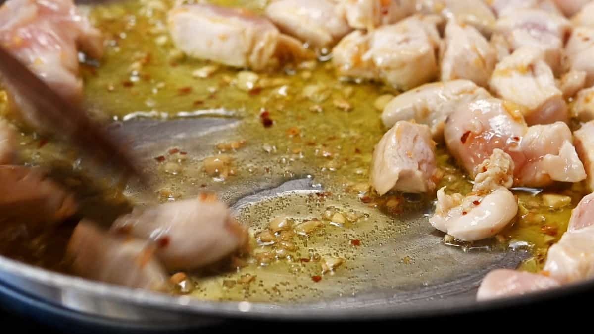 cooking chicken in garlic mixture in skillet.