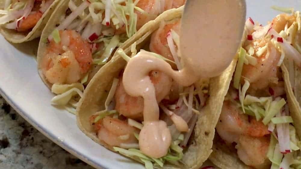 drizzling sauce over shrimp tacos