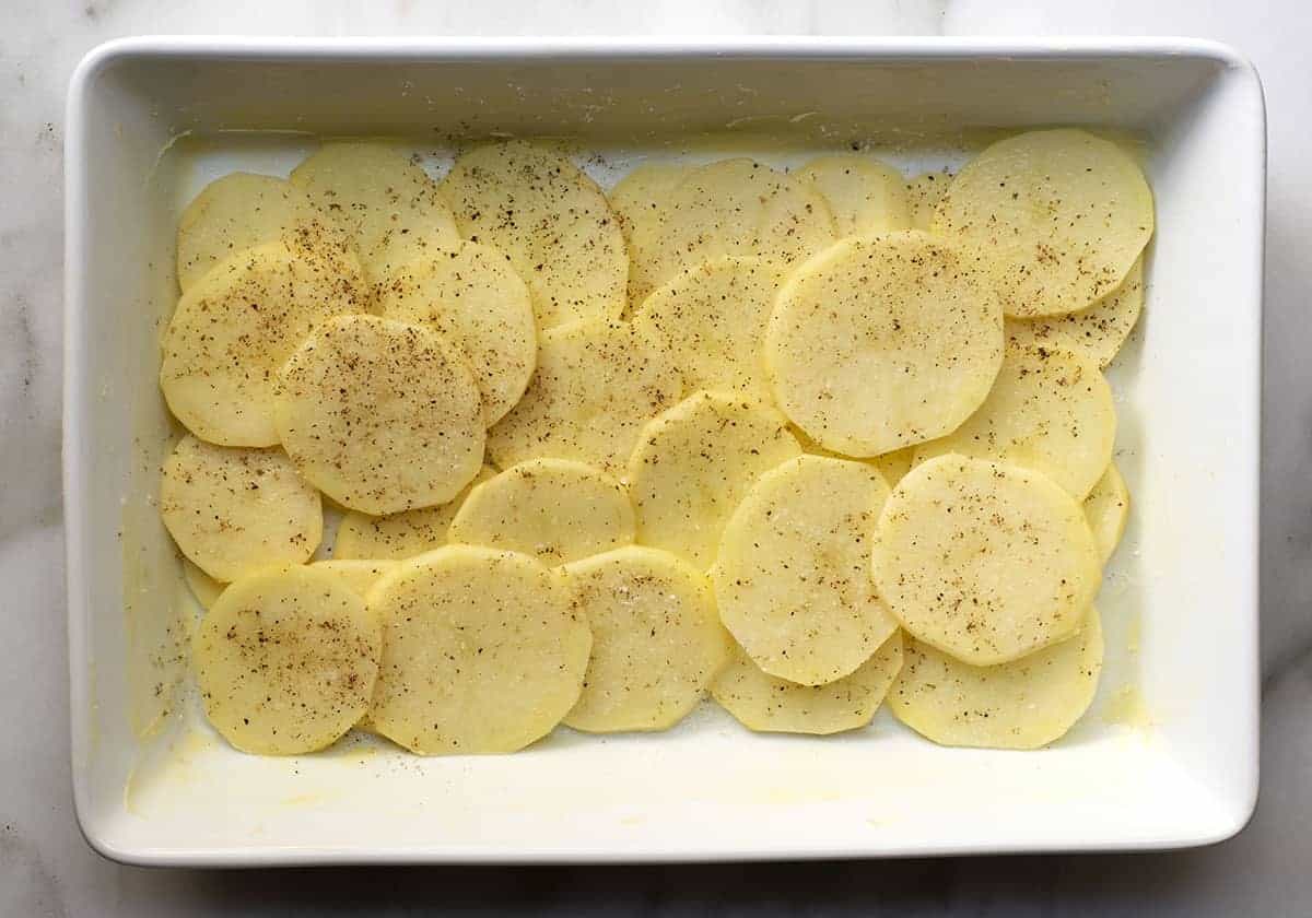 first layer of sliced potatoes in baking dish