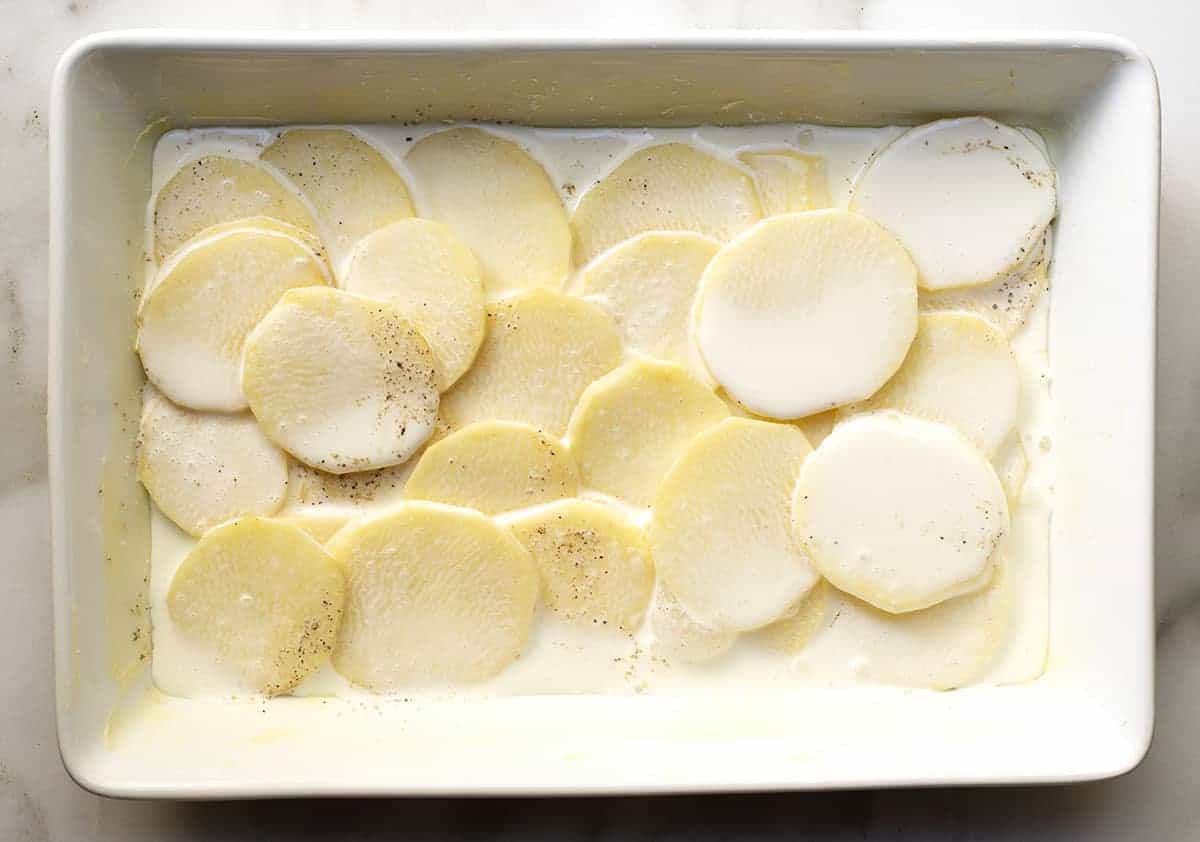 first layer of sliced potatoes with cream mixture in baking dish