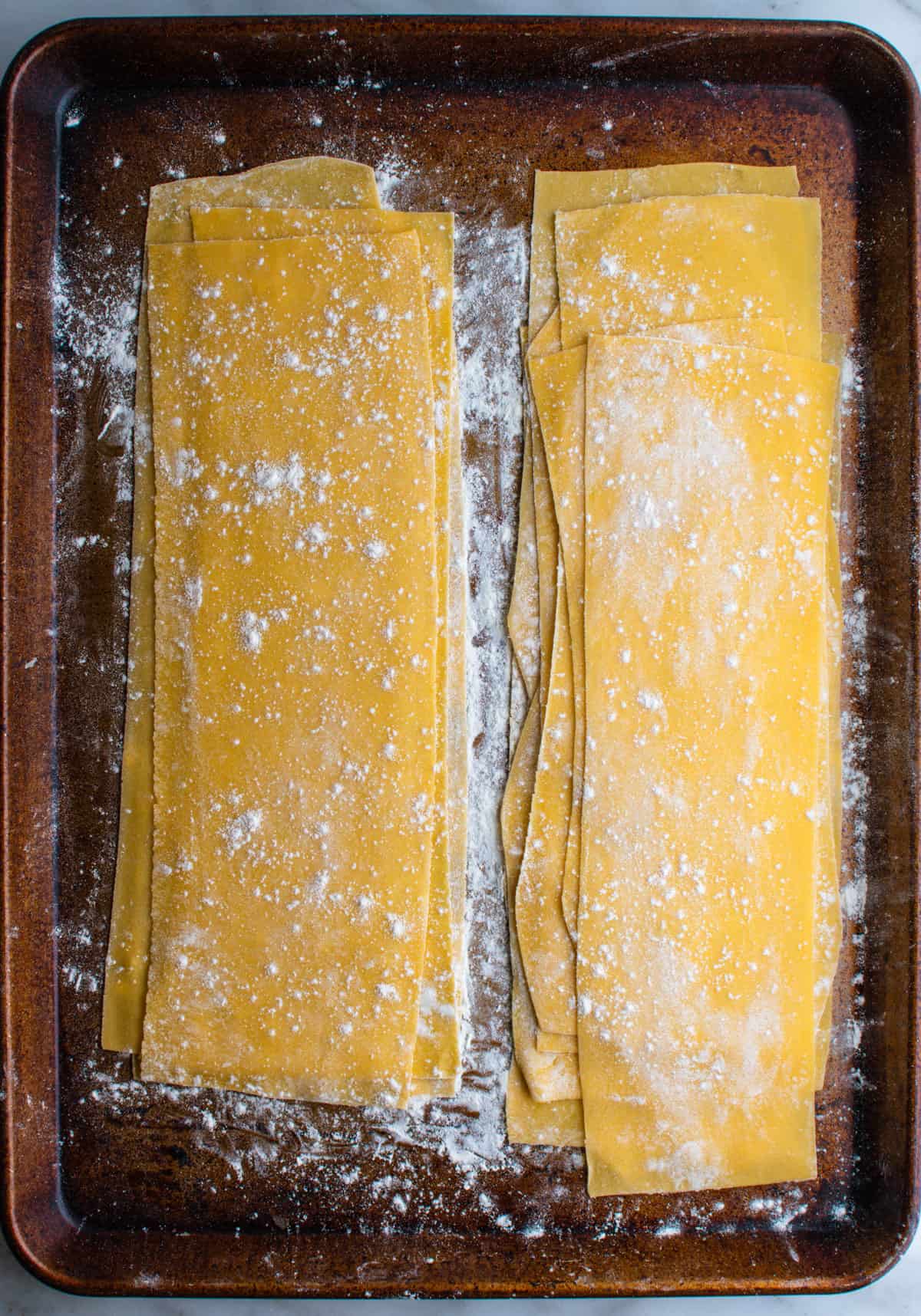 homemade lasagna noodles on a floured baking sheet