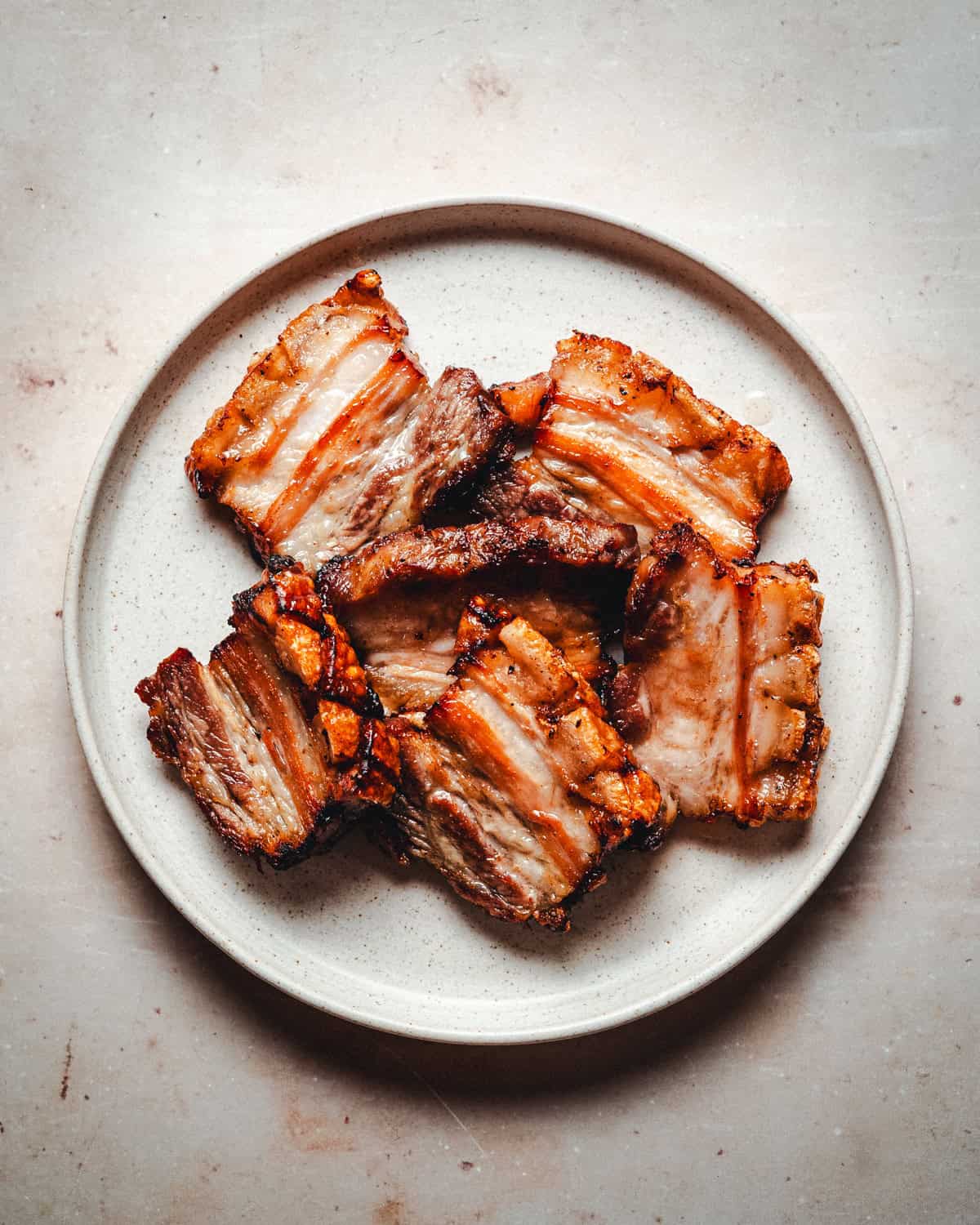 Sliced crispy pork belly served on a plate after being crisped up in a pan.