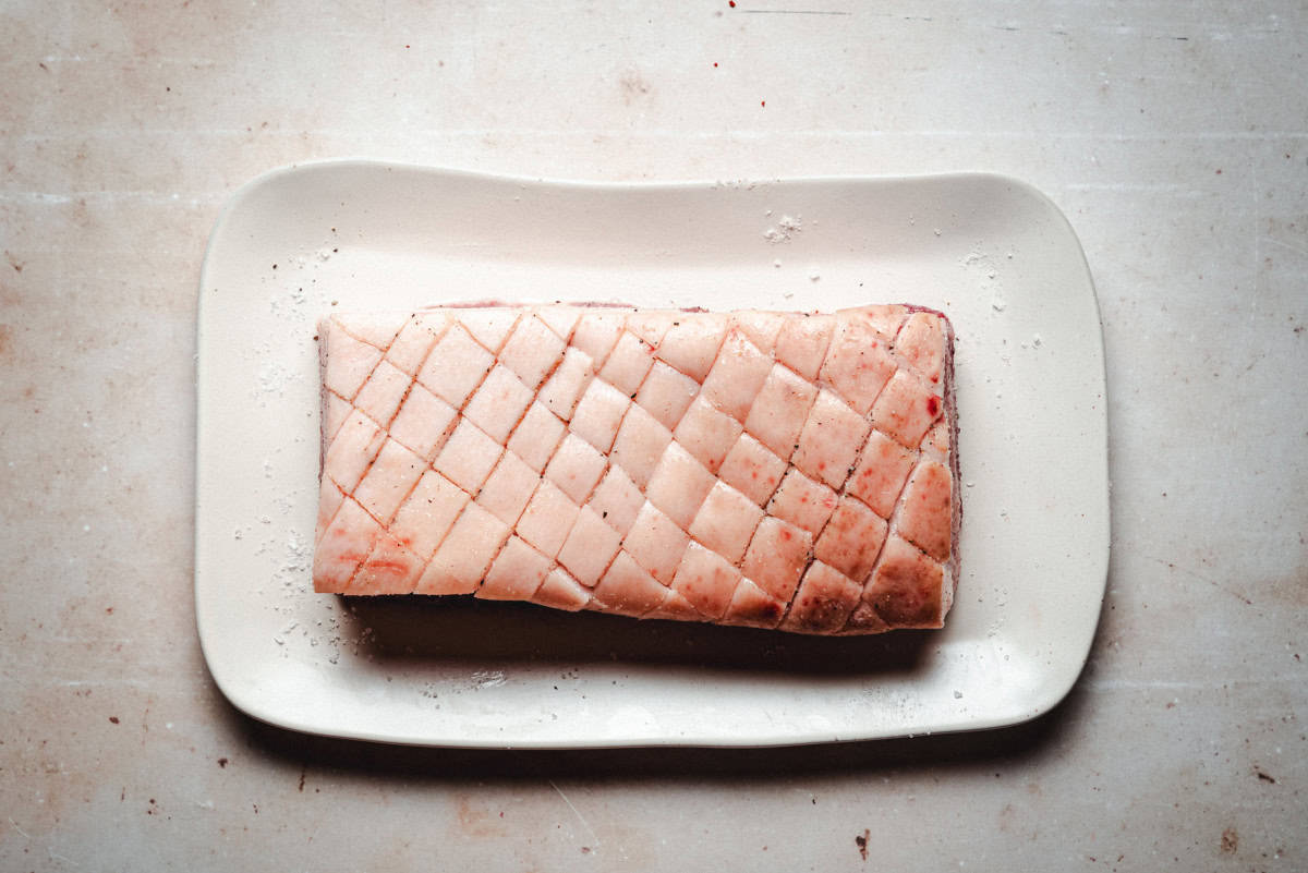 Skin on pork belly, seasoned with salt and pepper scored through skin at diagonal every half inch.