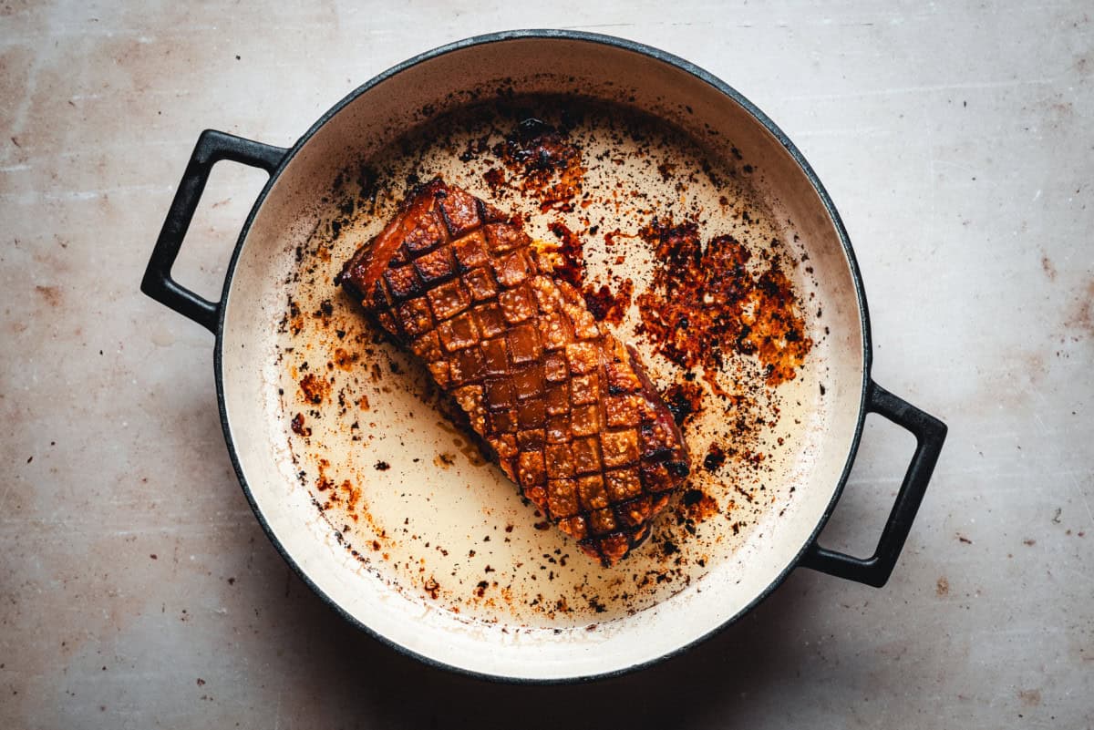 Fully cooked, crispy skin on pork belly in bottom of cast iron pan.