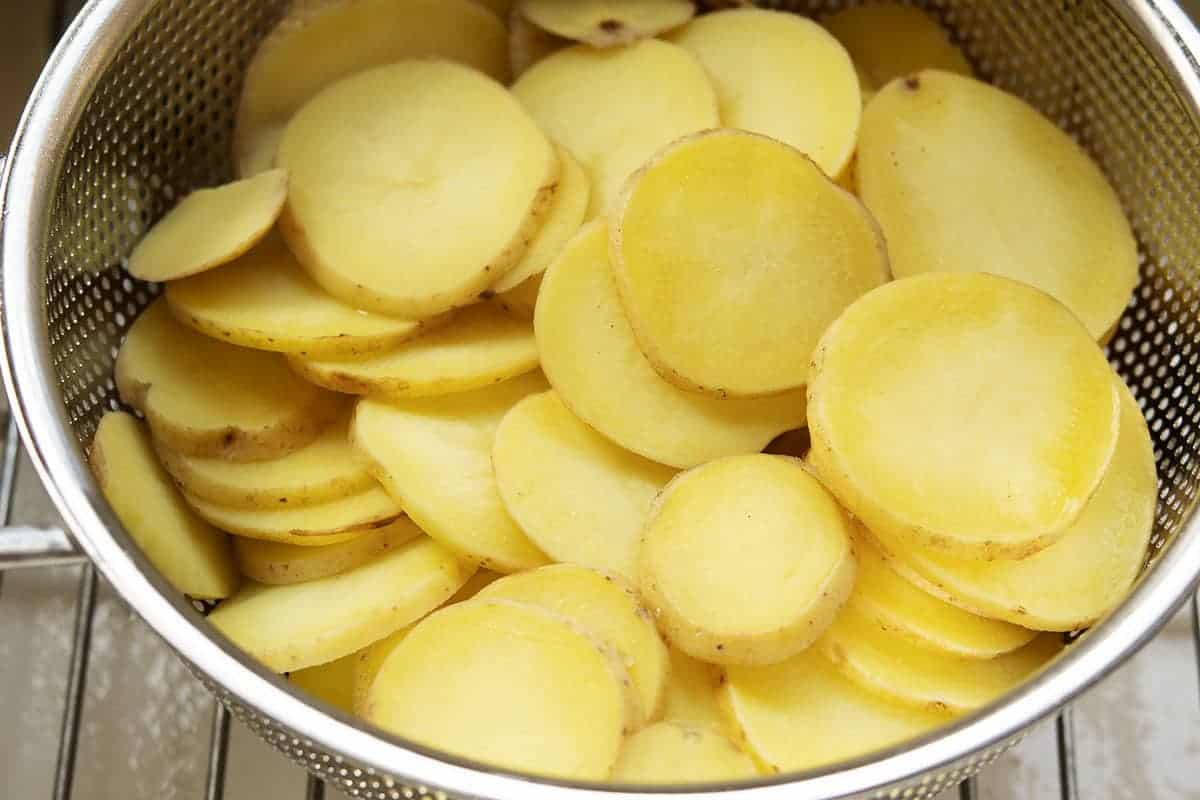 parboiled sliced potatoes in collander