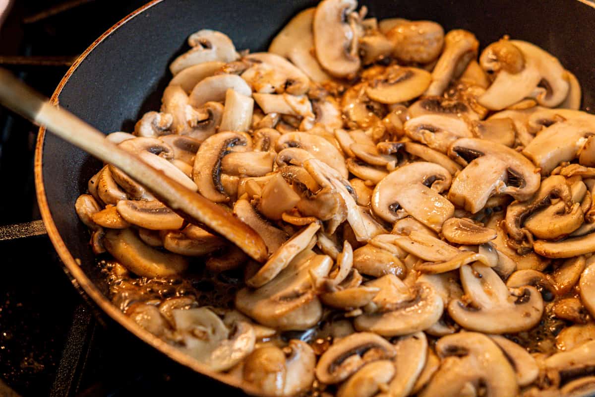 partially cooked mushrooms in a skillet.