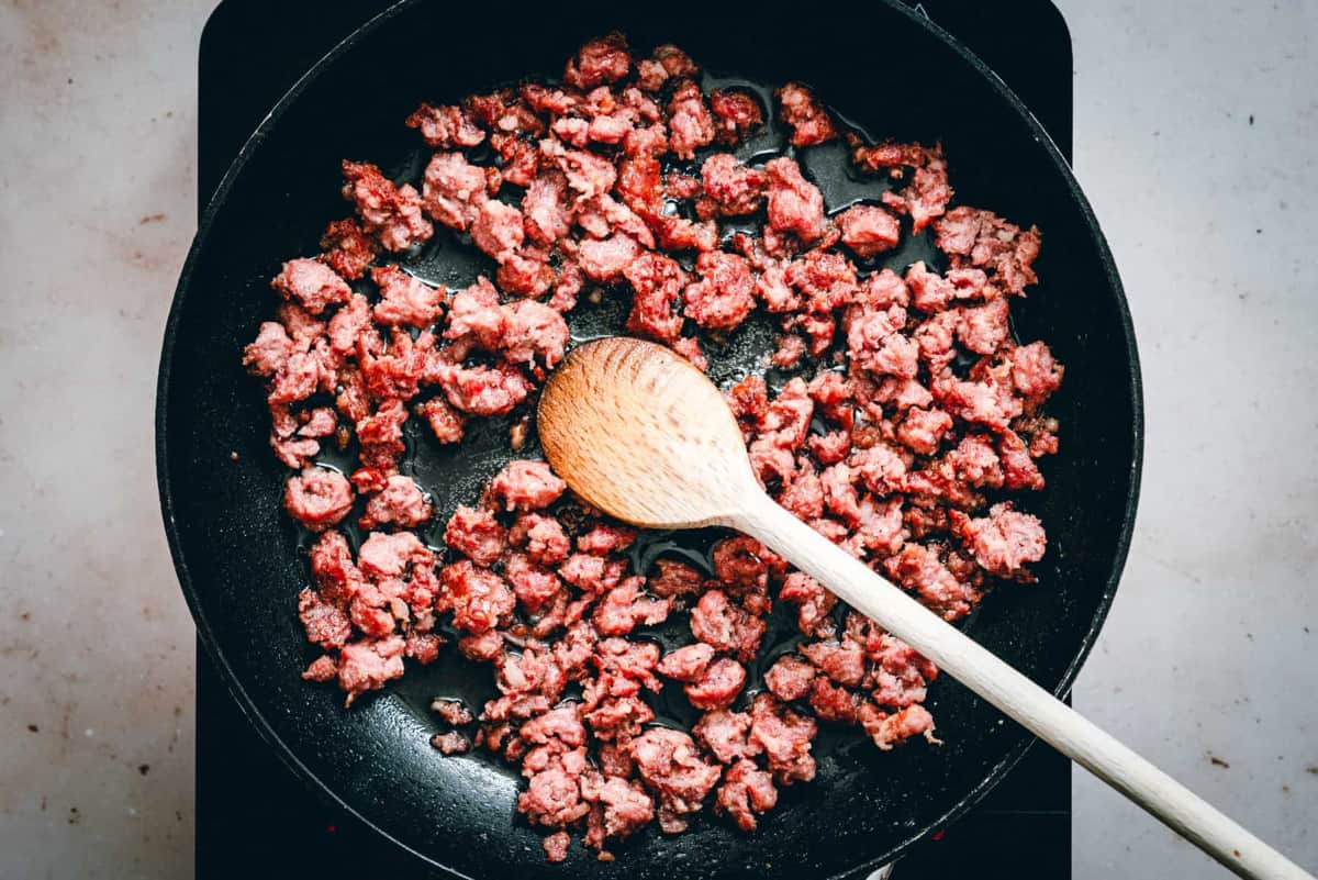 partially cooked sausage in a skillet.