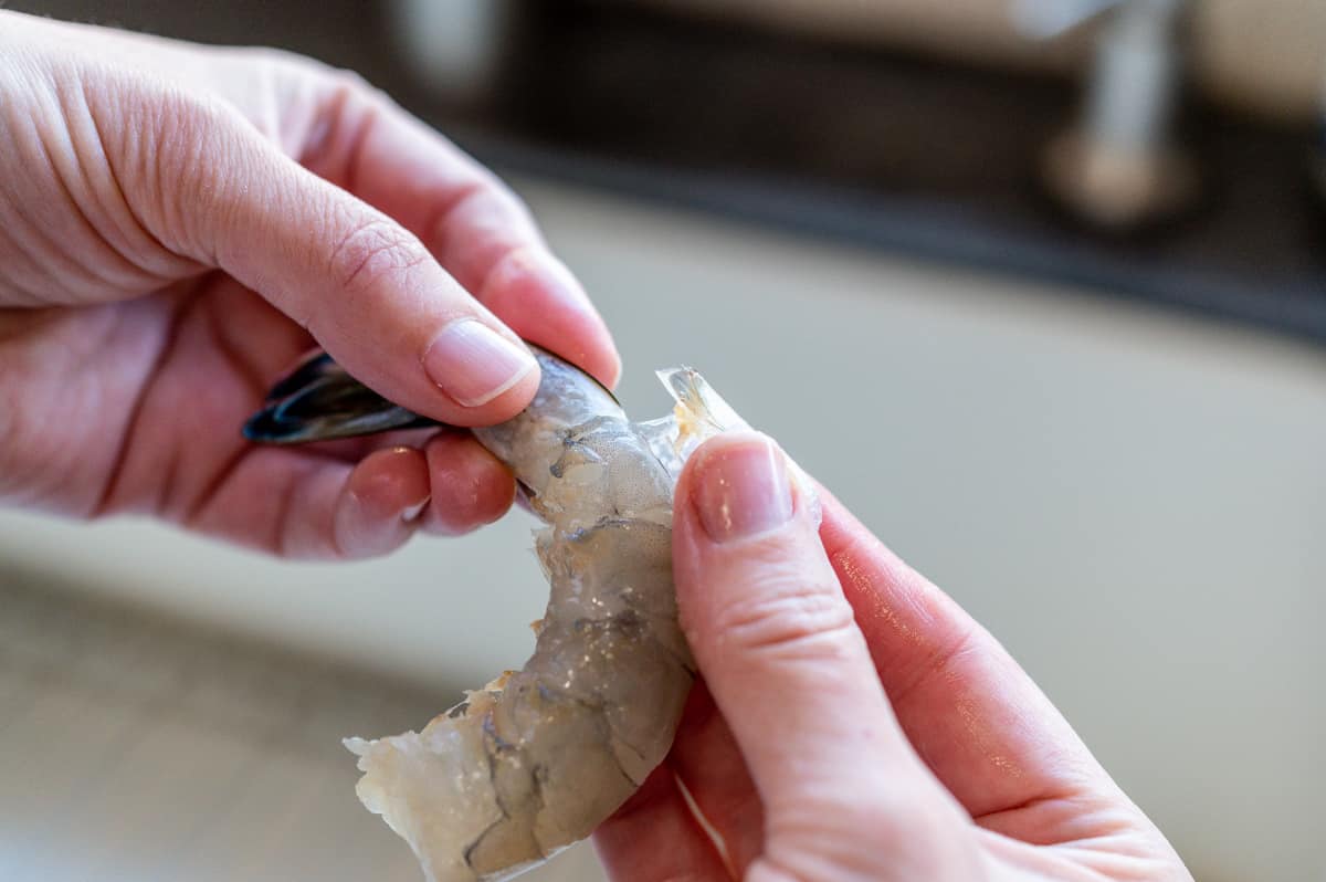 peeling the shell off of a raw shrimp.