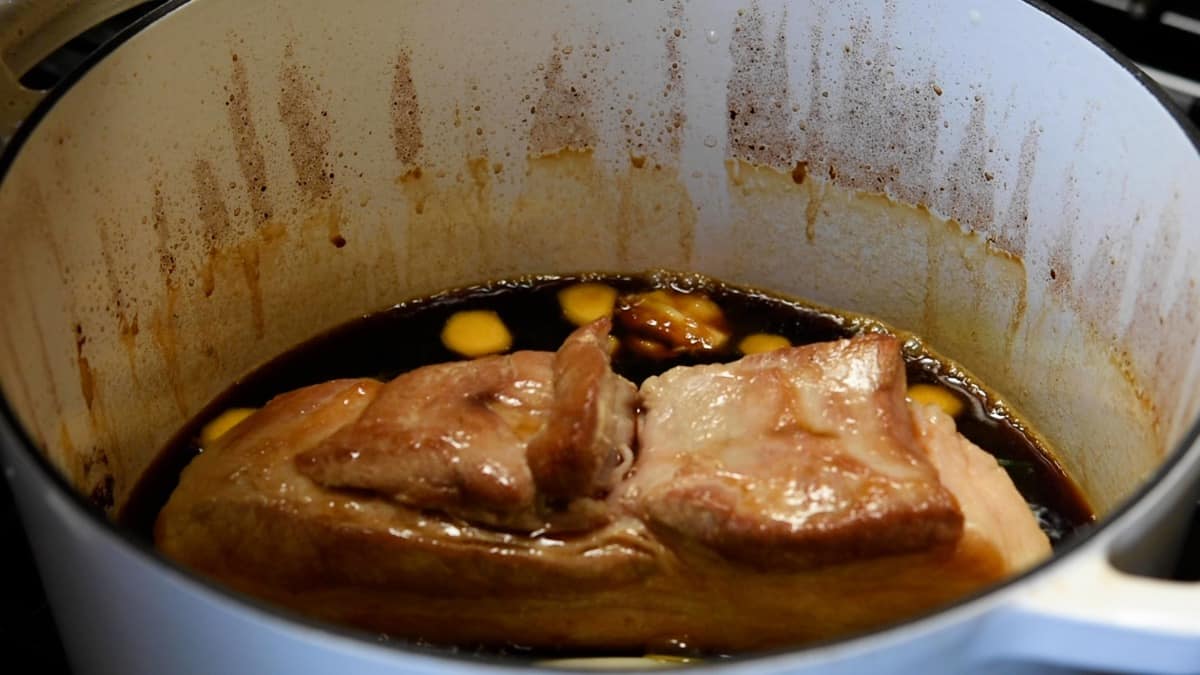 pork belly in braising sauce with aromatics in dutch oven