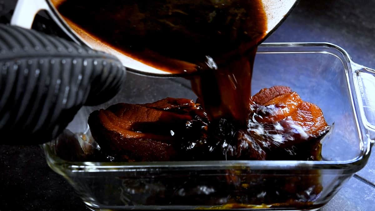 pouring braising liquid over cooked pork belly