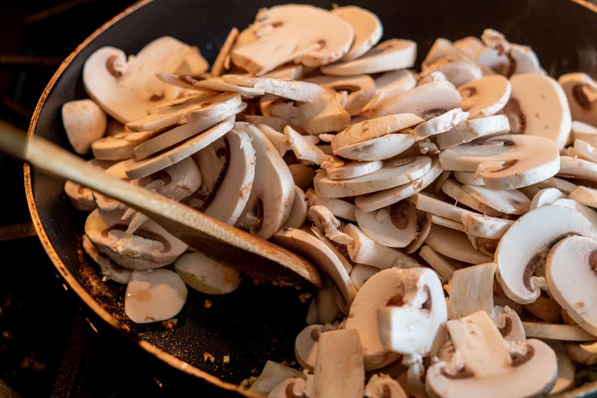 raw sliced mushrooms in a skillet.