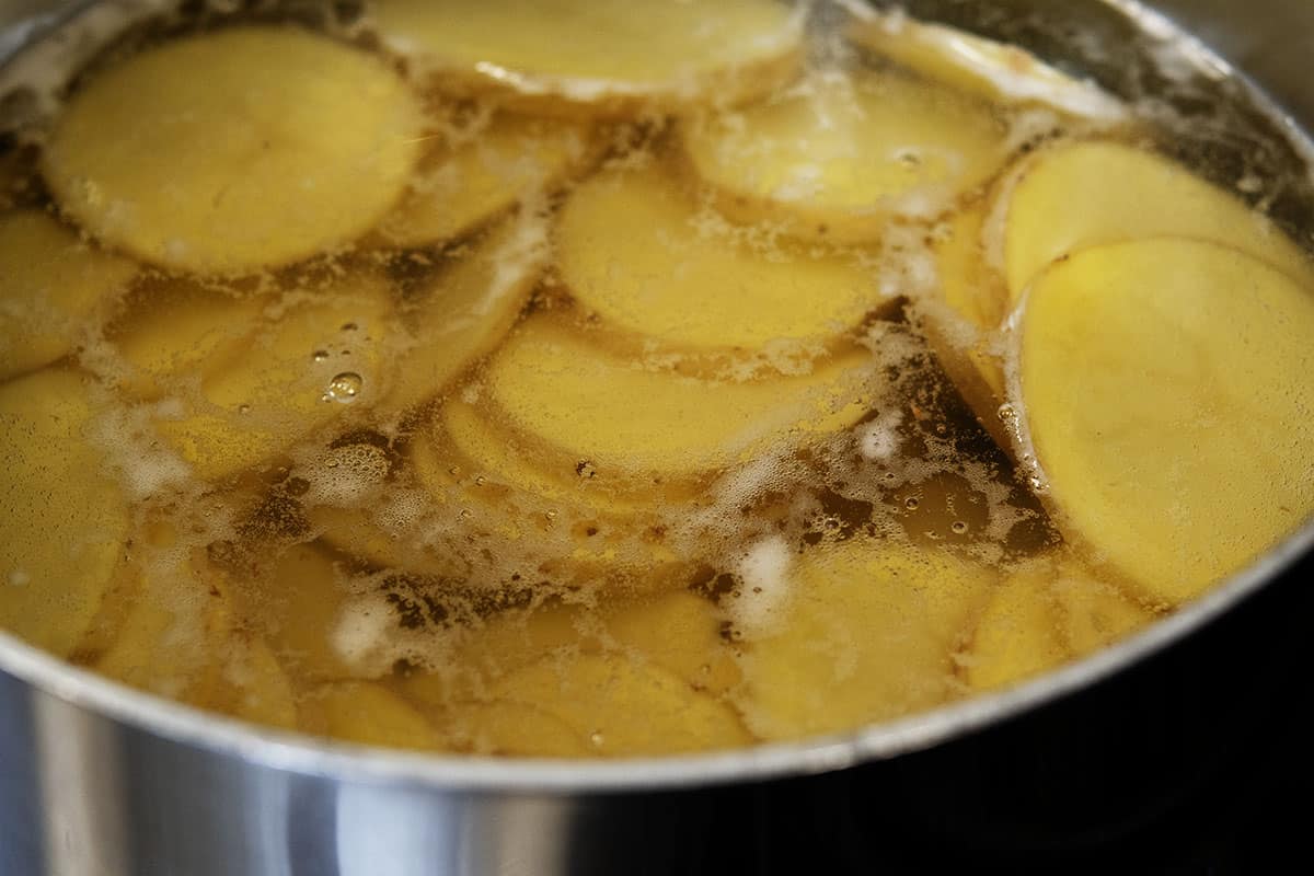 sliced potatoes in saucepan of water