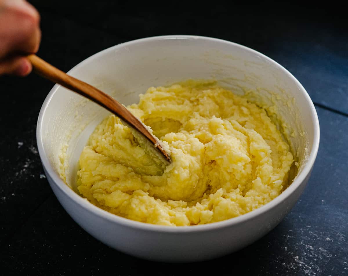 stirring butter garlic and cream mixture into riced potatoes.