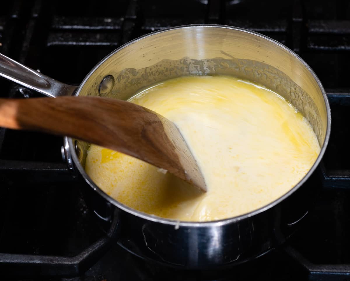 stirring cream into garlic and butter mixture in saucepan.