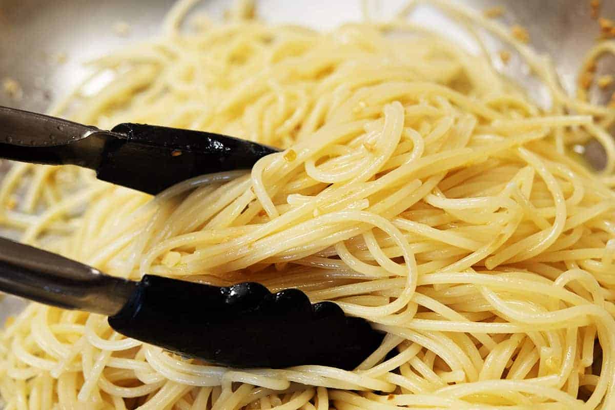 tossing pasta with garlic butter sauce