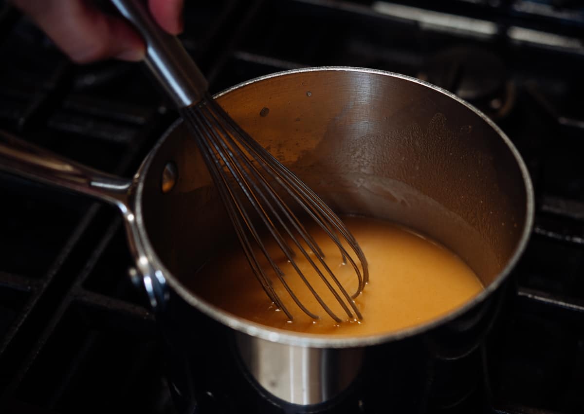 whisking toasted flour and brown butter mixture into simmering chicken broth.