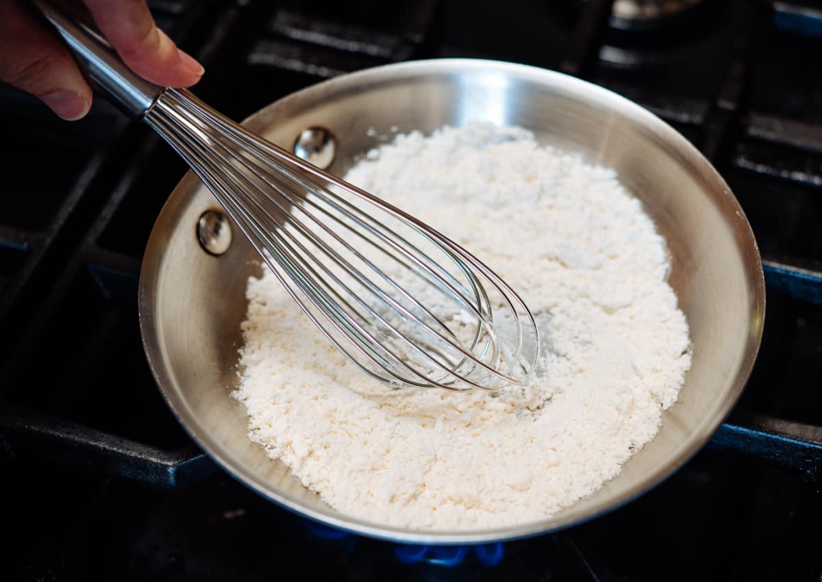 whisking white flour in a skillet.